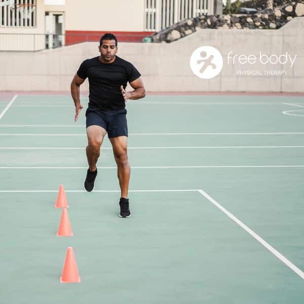 Athlete running a cone agility drill on an outdoor court while training to return to sports after injury